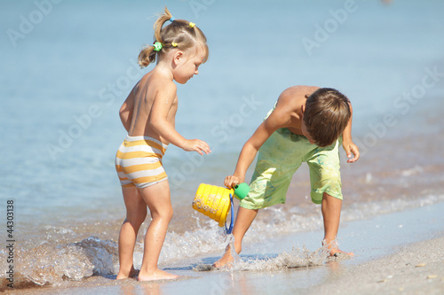 Photo: outdoor portrait of two children playing with water on sand beac outdoor portrait of two children playing with water on sand beac