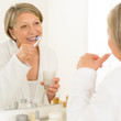 Foto: Senior woman brushing teeth bathroom mirror reflection Senior woman brushing teeth bathroom mirror reflection