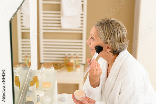 Photo: Senior woman apply make-up powder in bathroom Senior woman apply make-up powder in bathroom