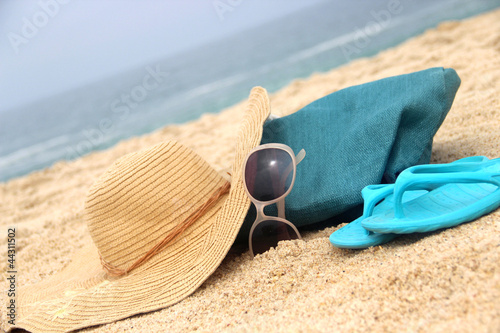 Photo: Blue beach bag on the seacoast and straw hat Blue beach bag on the seacoast and straw hat