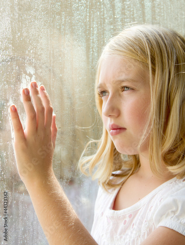 Photo: teen or child looking out a window teen or child looking out a window