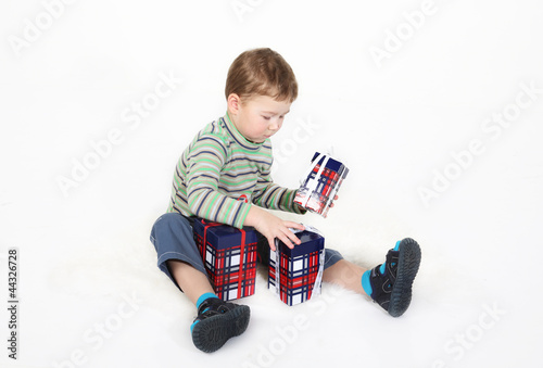 Photo: boy sits and plays with gift boxes boy sits and plays with gift boxes