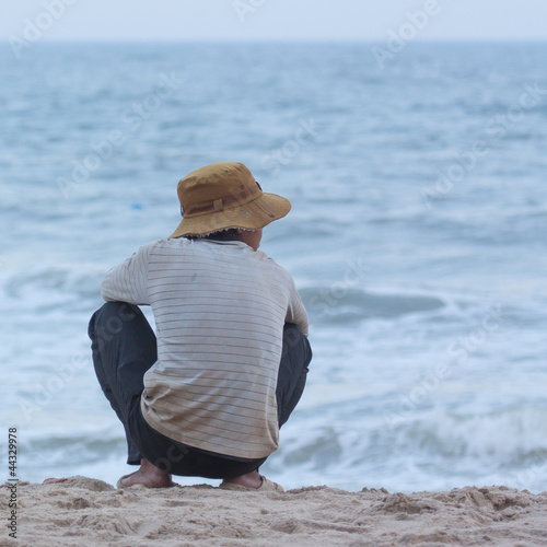 Photo: Man sitting on the beach at the south chinese sea Man sitting on the beach at the south chinese sea