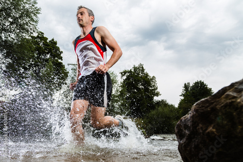 Photo: Jogger durchquert ein Bachbett Jogger durchquert ein Bachbett