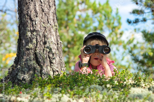 Photo: Little girl looking through binoculars with a surprised face Little girl looking through binoculars with a surprised face