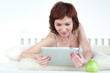 Photo: woman with an green apple and tablet at bed reading ebook woman with an green apple and tablet at bed reading ebook