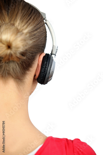 Photo: Girl listening to music with headphones, back view Girl listening to music with headphones, back view