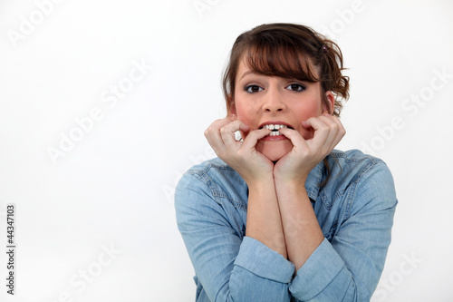 Foto: Woman biting her nails. Woman biting her nails.