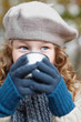 Girl in grey beret drinking from flask cup