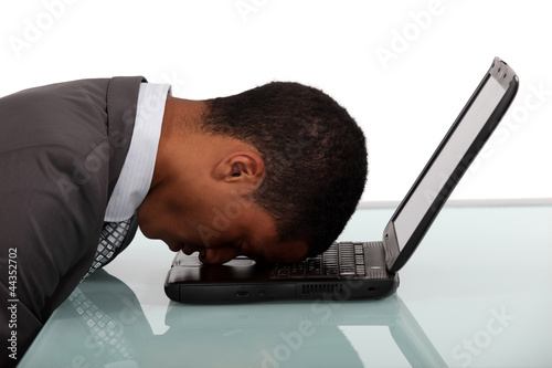 Photo: exhausted businessman sleeping over his laptop exhausted businessman sleeping over his laptop