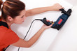 handywoman drilling a hole in the ceiling