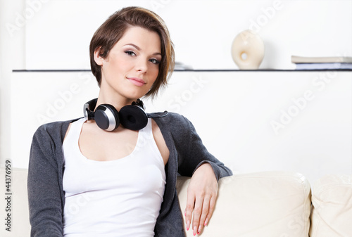 Photo: Sitting on the white leather sofa pretty woman with headphones Sitting on the white leather sofa pretty woman with headphones