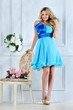 Beautiful blonde woman in blue dress in luxury interior.