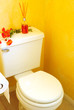 Toilet in Yellow Bathroom with Diffuser and Flowers