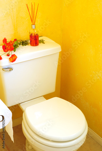 Photo: Toilet in Yellow Bathroom with Diffuser and Flowers Toilet in Yellow Bathroom with Diffuser and Flowers