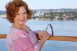 Happy woman with sunglasses stands near railing at ship deck