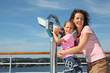 Mother and daughter stand on deck of ship near big binoculars