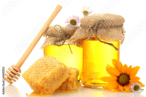 Photo: Sweet honey in jars with honeycomb, wooden drizzler and flowers Sweet honey in jars with honeycomb, wooden drizzler and flowers