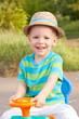 Photo: Laughing baby in a hat driving a toy car Laughing baby in a hat driving a toy car
