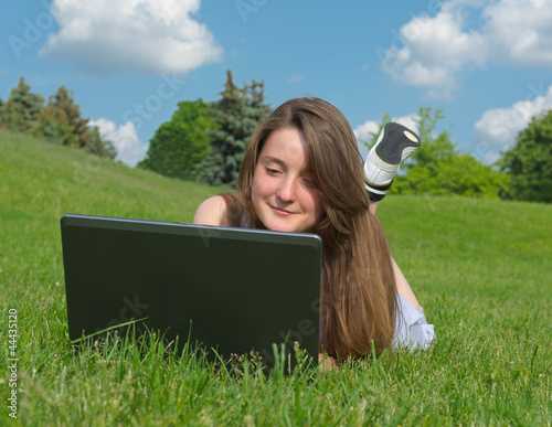 Photo: Smiling woman using a laptop outdoors Smiling woman using a laptop outdoors