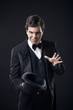 Foto: magician showing tricks with top hat isolated on dark background magician showing tricks with top hat isolated on dark background