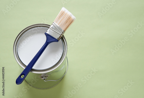 Photo: Paintbrush and a can of white paint on green background Paintbrush and a can of white paint on green background