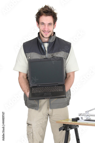 Photo: Young tiler holding a laptop with a blank screen Young tiler holding a laptop with a blank screen