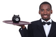 Photo: Waiter holding a piggy bank on his tray Waiter holding a piggy bank on his tray