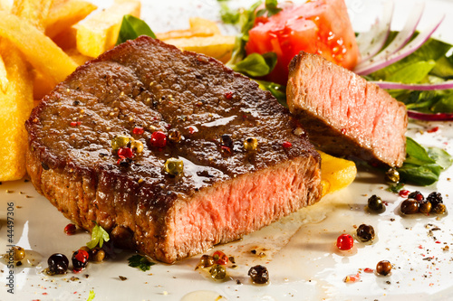 Photo: Grilled steaks, French fries and vegetables Grilled steaks, French fries and vegetables