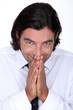 Man in a shirt and tie pressing his hands together in glee