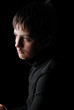 Sad teenage boy in black, low key