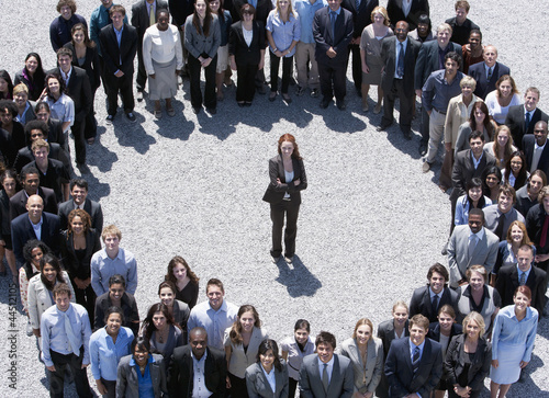 Photo: Portrait of businesswoman standing at center of circle formed by business people Portrait of businesswoman standing at center of circle formed by business people