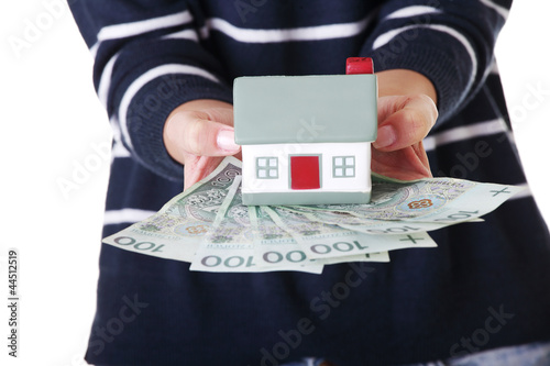 Photo: Woman holding PLN bills and house model over white. Woman holding PLN bills and house model over white.