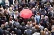 Red umbrella at center of business people in huddle