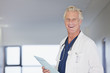 Portrait of smiling doctor holding medical record in hospital corridor