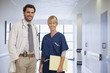Portrait of smiling doctor and nurse in hospital corridor