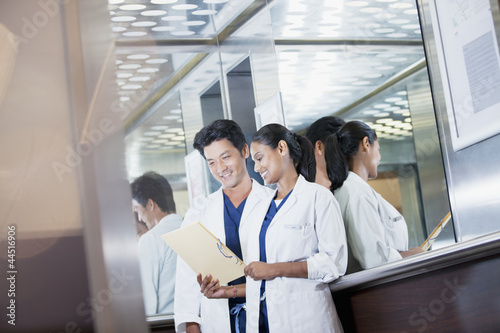 Photo: Smiling doctors reviewing medical record in hospital elevator Smiling doctors reviewing medical record in hospital elevator
