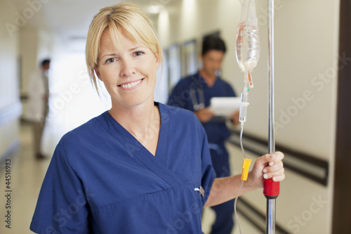 Photo: Portrait of smiling nurse with IV drip in hospital corridor Portrait of smiling nurse with IV drip in hospital corridor