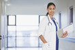 Portrait of smiling doctor with notepad in hospital corridor
