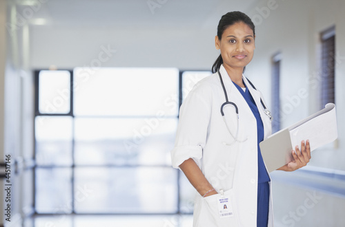 Photo: Portrait of smiling doctor with notepad in hospital corridor Portrait of smiling doctor with notepad in hospital corridor