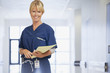 Portrait of smiling nurse holding medical record in hospital corridor