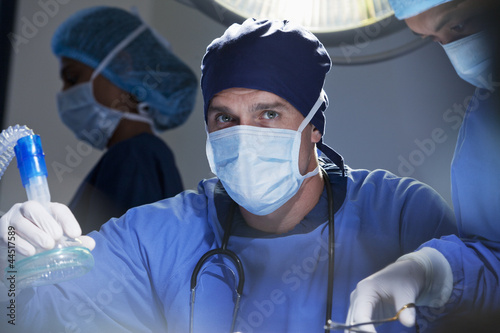 Photo: Portrait of serious surgeon holding oxygen mask in operating room Portrait of serious surgeon holding oxygen mask in operating room