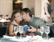 Foto: Man kissing and giving gift to woman in restaurant Man kissing and giving gift to woman in restaurant