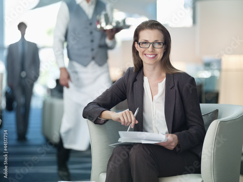 Photo: Portrait of smiling businesswoman working in hotel lounge Portrait of smiling businesswoman working in hotel lounge