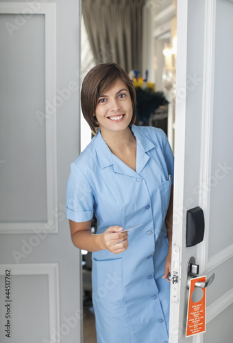 Photo: Portrait of smiling maid opening hotel room door Portrait of smiling maid opening hotel room door