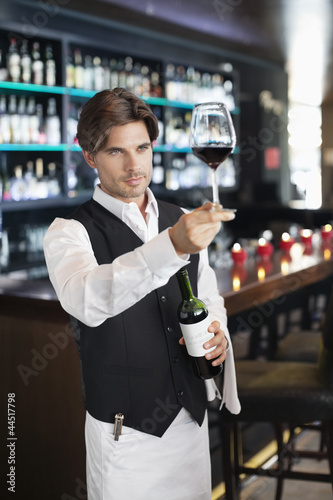 Photo: Sommelier examining glass of red wine in bar Sommelier examining glass of red wine in bar
