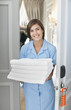 Portrait of smiling maid with towels in hotel room doorway