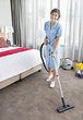 Portrait of smiling maid vacuuming hotel room