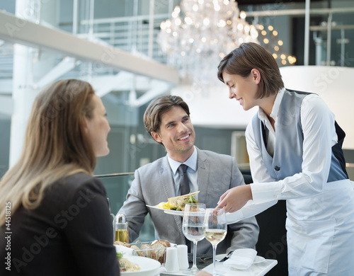 Photo: Waitress serving food to couple in restaurant Waitress serving food to couple in restaurant