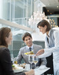 Waitress serving food to couple in restaurant